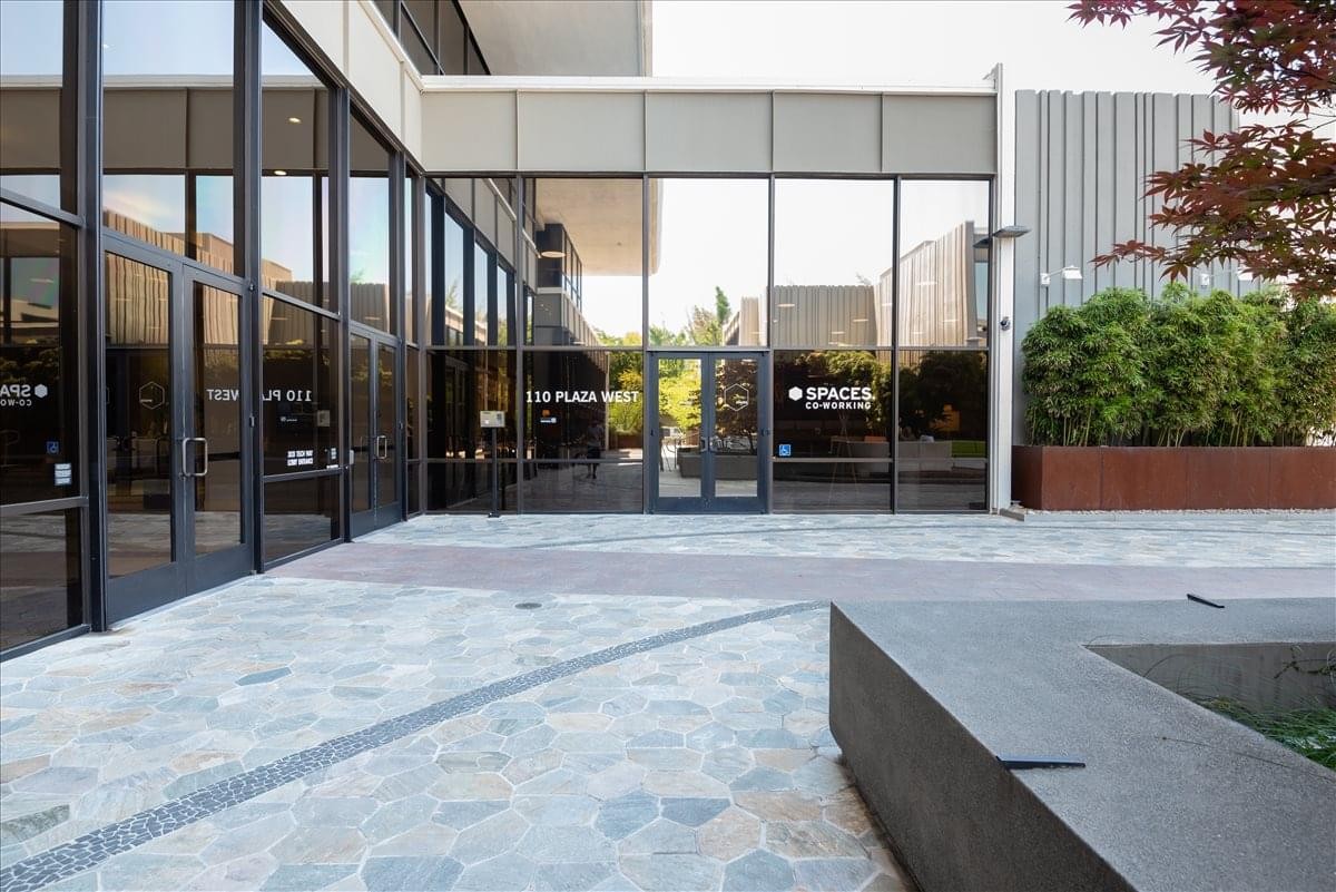 Exterior entrance of the modern glass-fronted 3031 Tisch Way, SPACES San Jose, Santana Row building.
