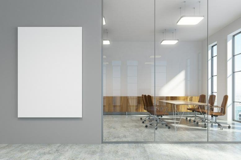 A private workstation with a white desk, laptop, and chrome lamp by a window.