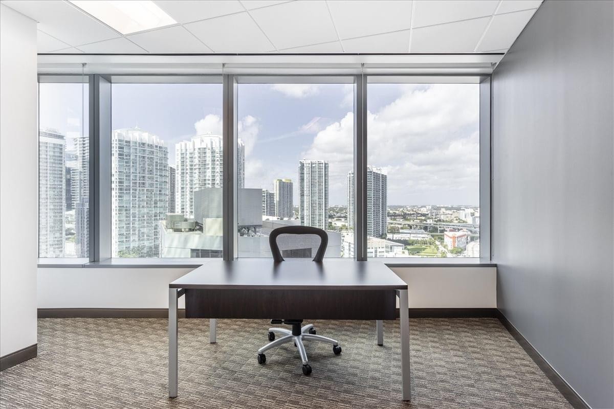 Private office featuring a dark wood desk and panoramic city views from the Wells Fargo Center.