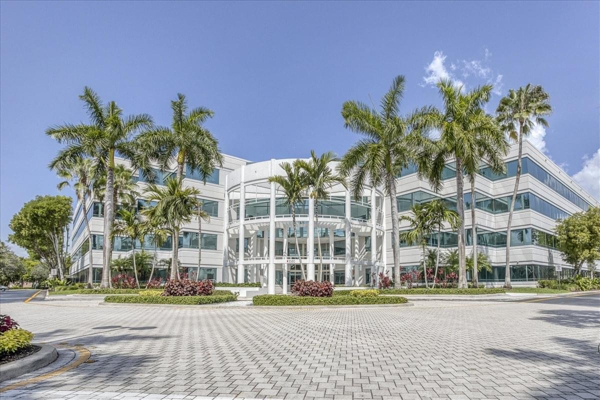 Exterior view of the white facade and palm trees at Huntington Square III Center.