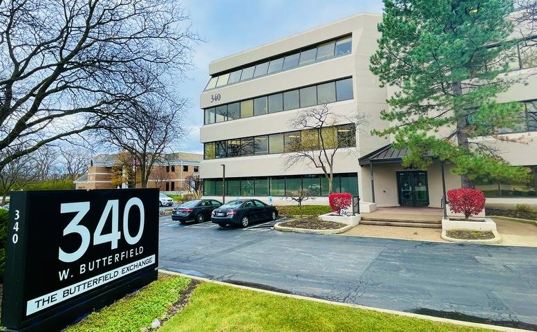 Exterior wide shot of the building facade with signage and landscaped entrance.