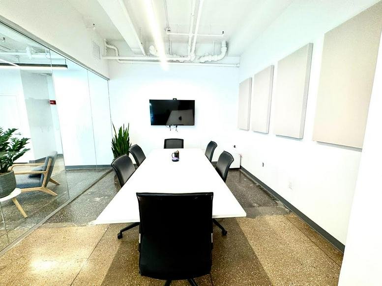 Bright white meeting room at 345 7th Avenue with a long table and acoustic wall panels.