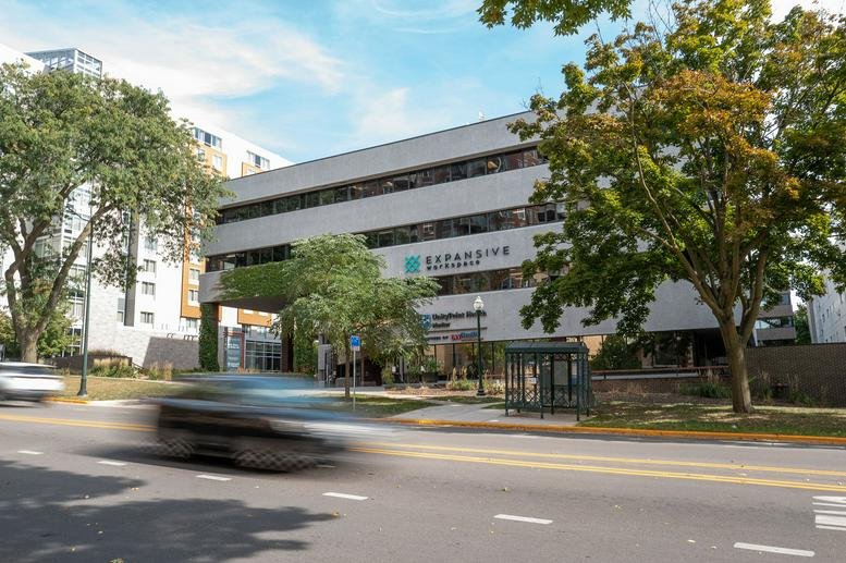 Wide view of the modern office building exterior with surrounding trees and street.