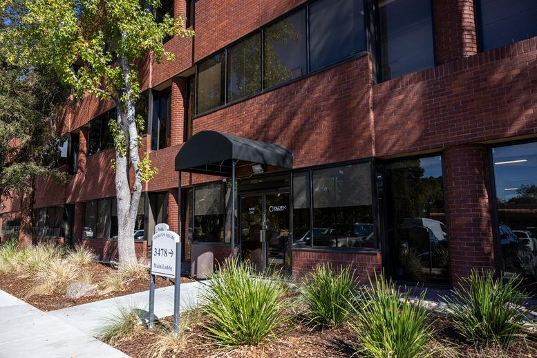 Exterior view of the brick building at 3478 Buskirk Street, Suite 1000 under a clear blue sky.