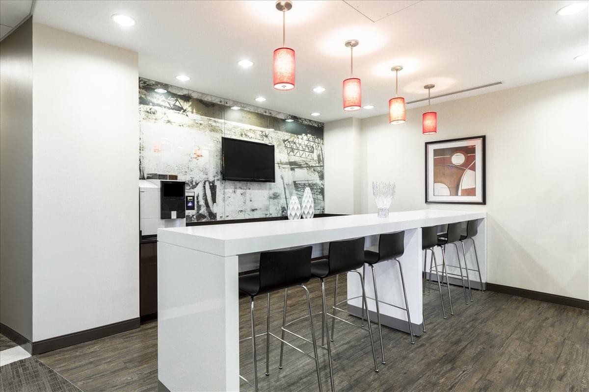 Modern breakroom at 3500 Lenox Rd with a long white counter, red pendant lights, and coffee station.
