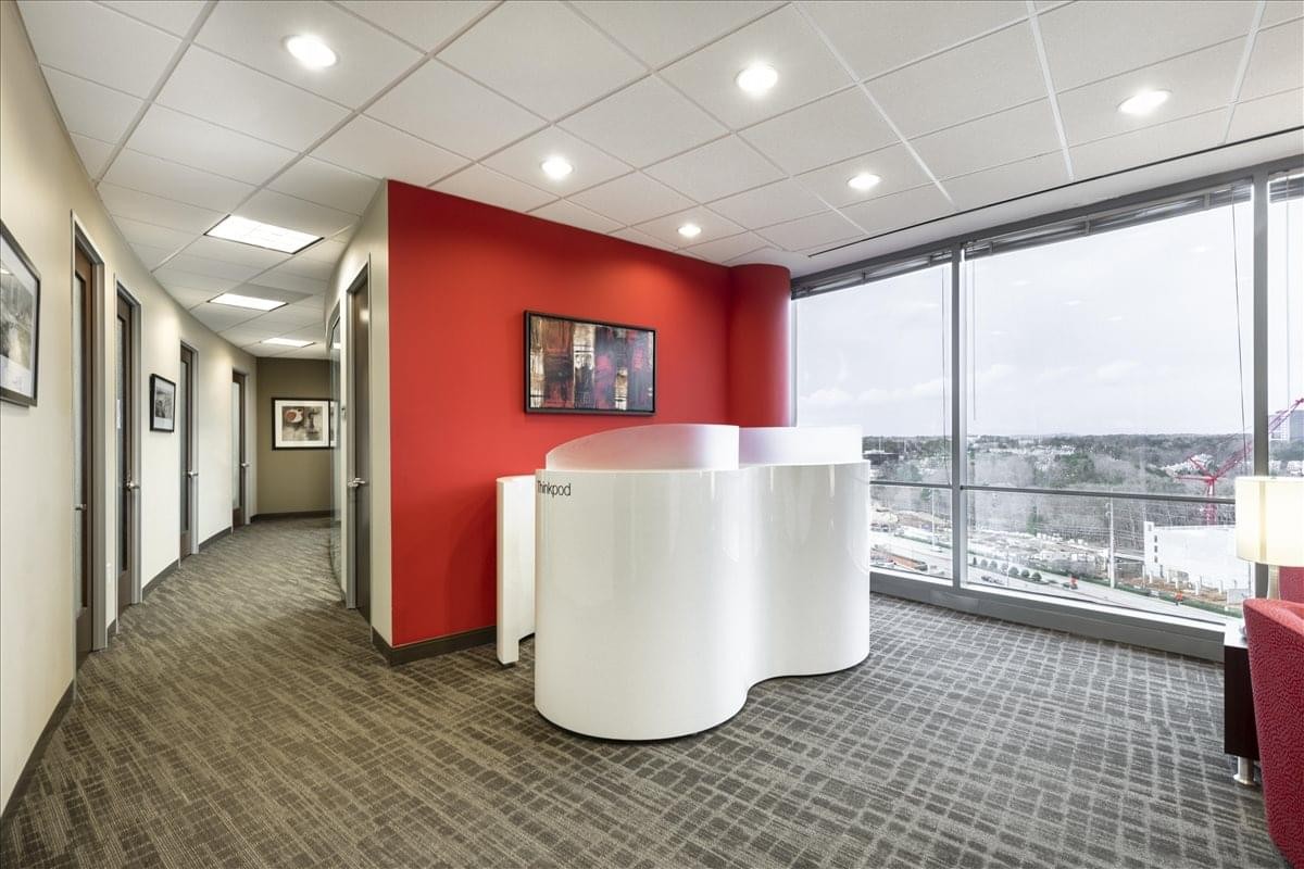 Stylish lobby area at 3500 Lenox Rd with a white curved reception desk and vibrant red accent wall.