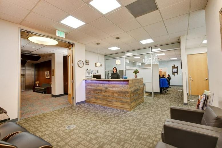 Reception area at 355 S Teller St, Suite 200, Lakewood, featuring a reclaimed wood desk and purple accent lighting.