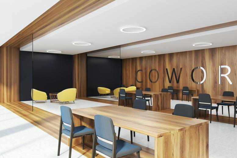 Modern coworking space at KPMG TOWER featuring wooden tables, blue chairs, and yellow armchairs.