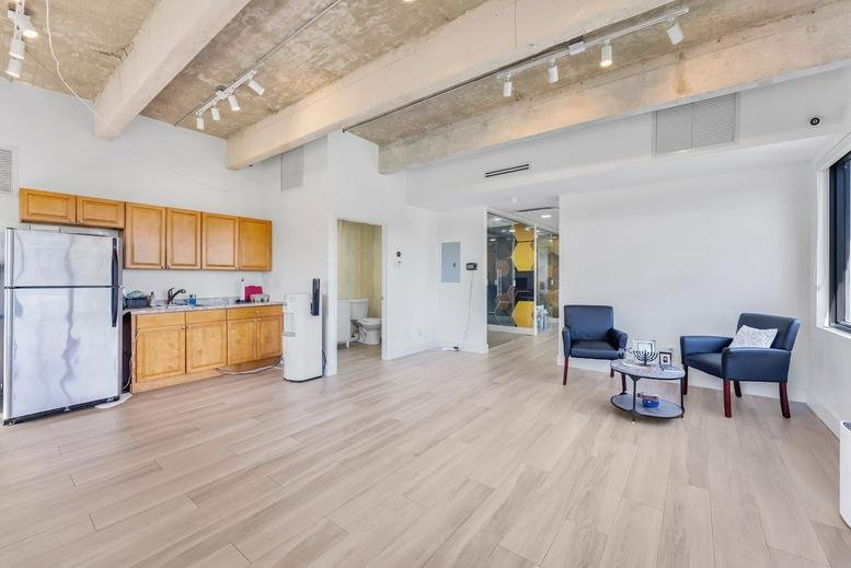 Spacious communal breakroom featuring a kitchenette with wooden cabinets and blue lounge chairs.