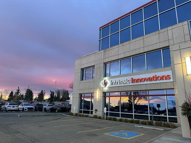 Exterior view of the Intrinsic Innovations building at sunset with a modern glass facade.