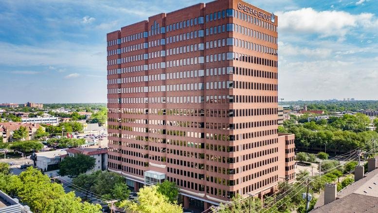Full-height view of the brick office building exterior surrounded by greenery.