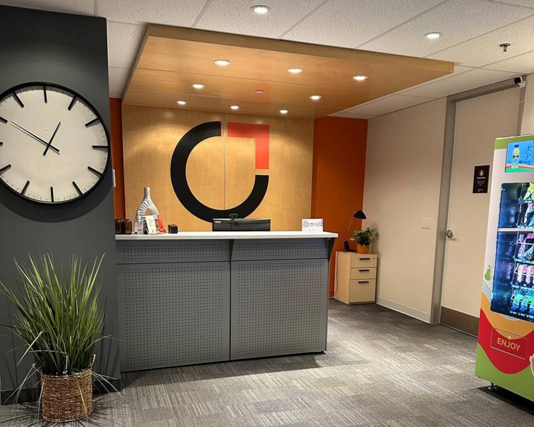 Modern reception area with a large circular logo, wooden canopy, and a digital snack kiosk at The Curators Hub.
