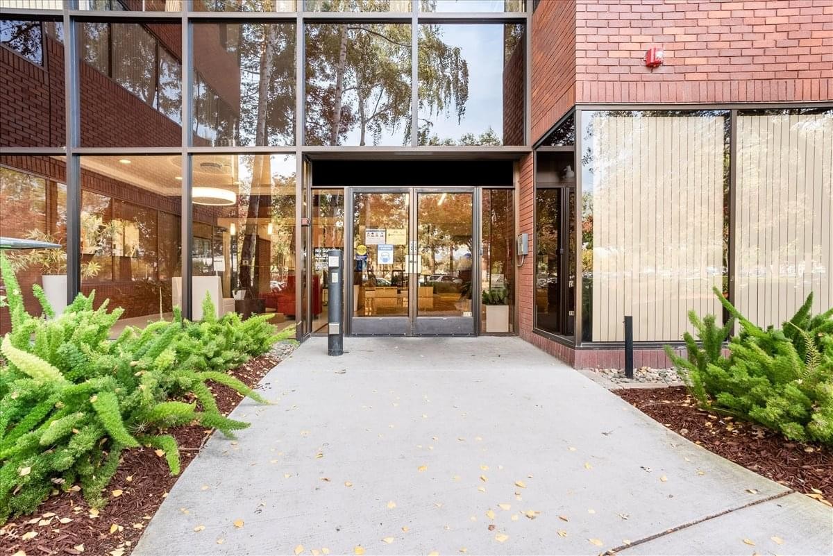 Ground floor entrance of 39899 Balentine Drive, Suite 200, featuring a glass facade and green shrubbery.