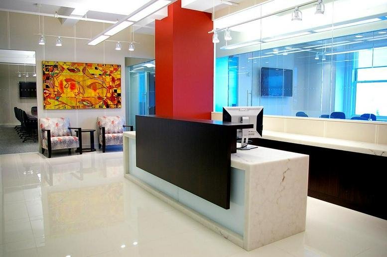 Reception area featuring a minimalist white desk and a vibrant abstract painting.