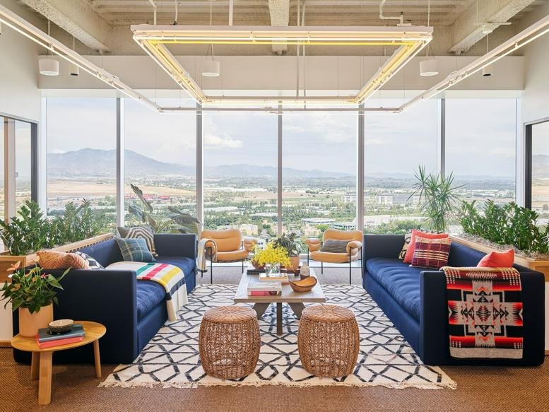 Colorful communal lounge with blue sofas and mountain views at 400 Spectrum Center Drive.