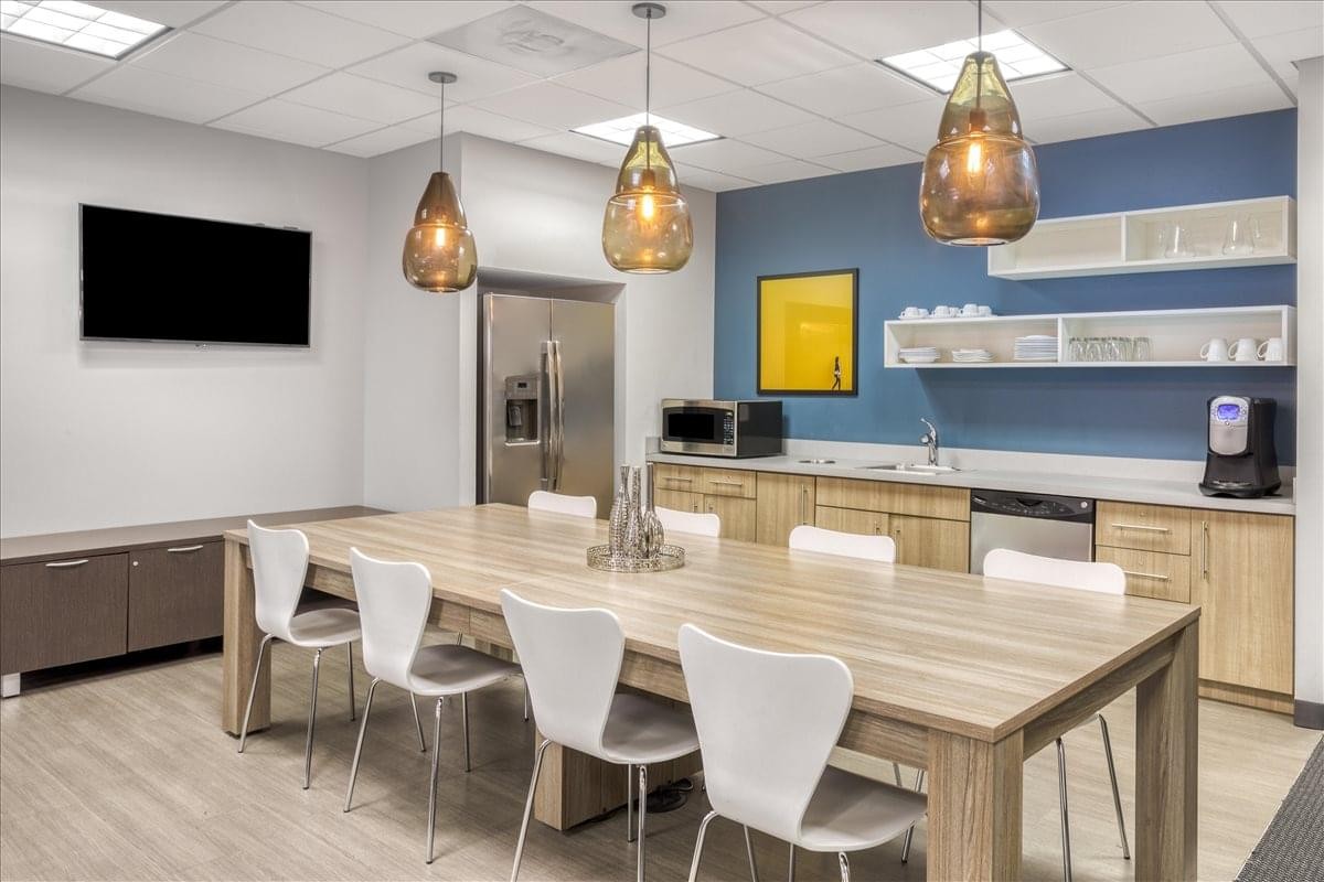 Spacious communal kitchen and dining area with blue accent wall and stylish pendant lights.