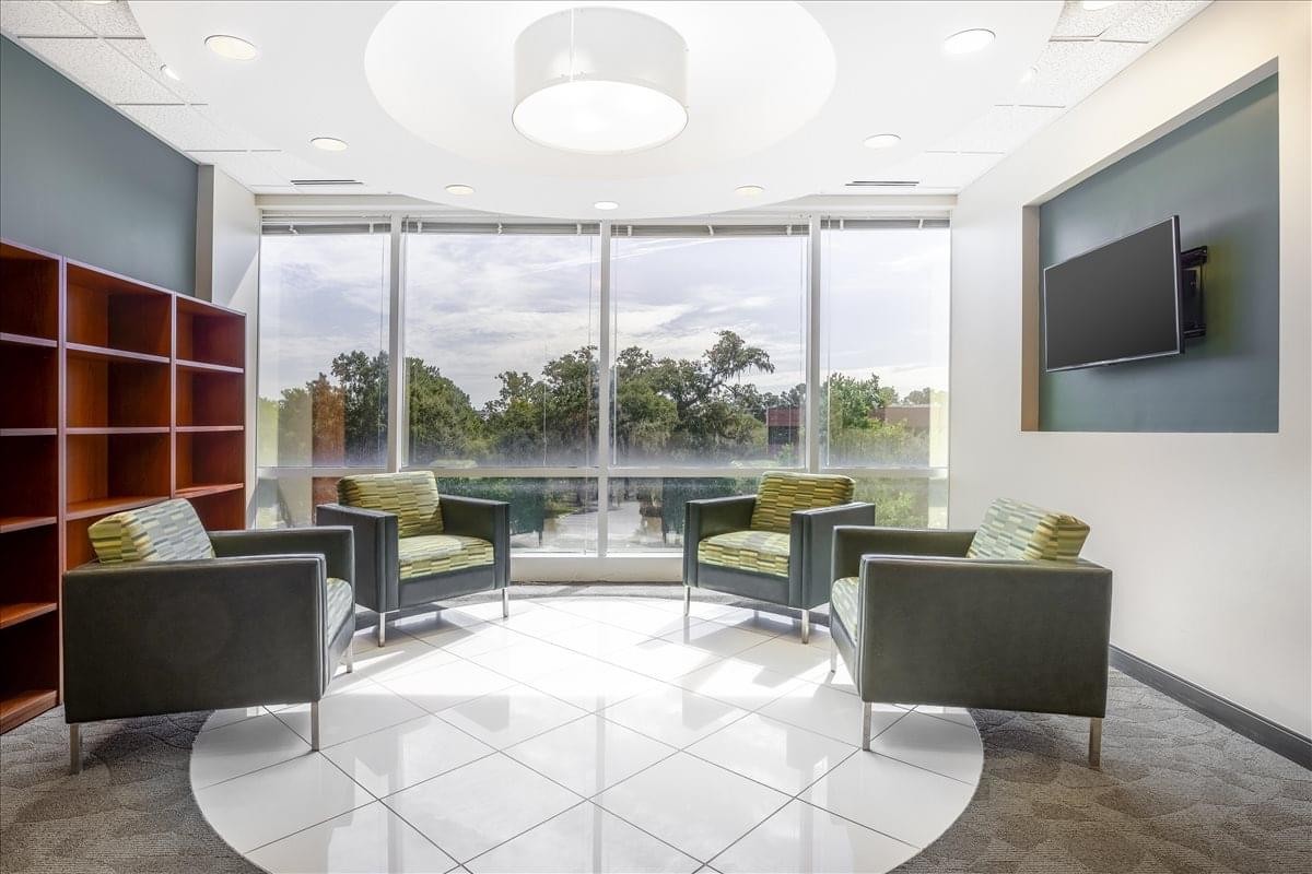 Sunlit lounge area with modern armchairs and floor-to-ceiling windows at 4000 S. Faber Place Drive.