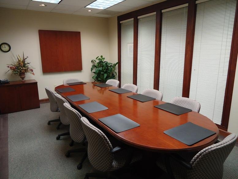 Spacious boardroom with a polished wood table and large windows at 4030 Wake Forest Road, Suite 300.