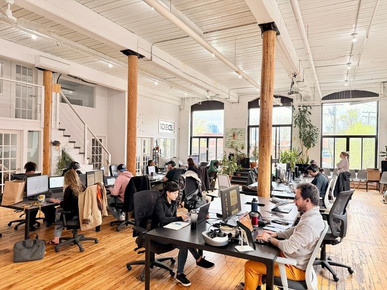 Spacious communal coworking area at IDEAL Coworking, Rue Saint-Ambroise with high ceilings and industrial pillars.