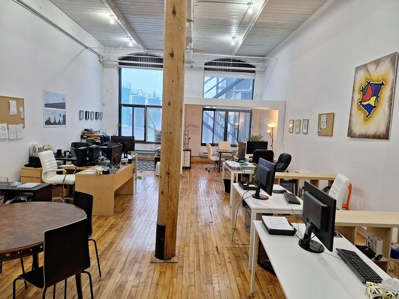 Spacious loft-style office at 4035 Rue St-Ambroise with exposed wooden pillars and high ceilings.
