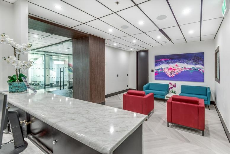 Reception area featuring a marble-topped front desk and a colorful lounge with red and blue seating.