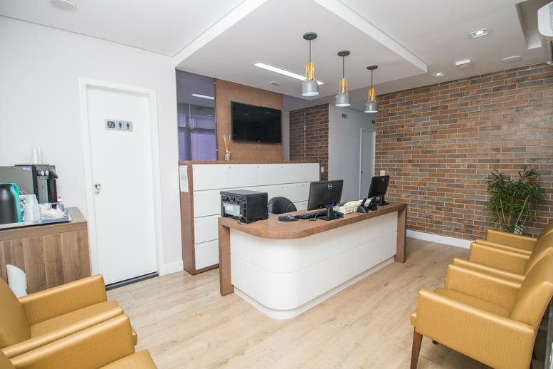Modern reception area with a curved white desk, brick feature wall, and comfortable lounge seating.