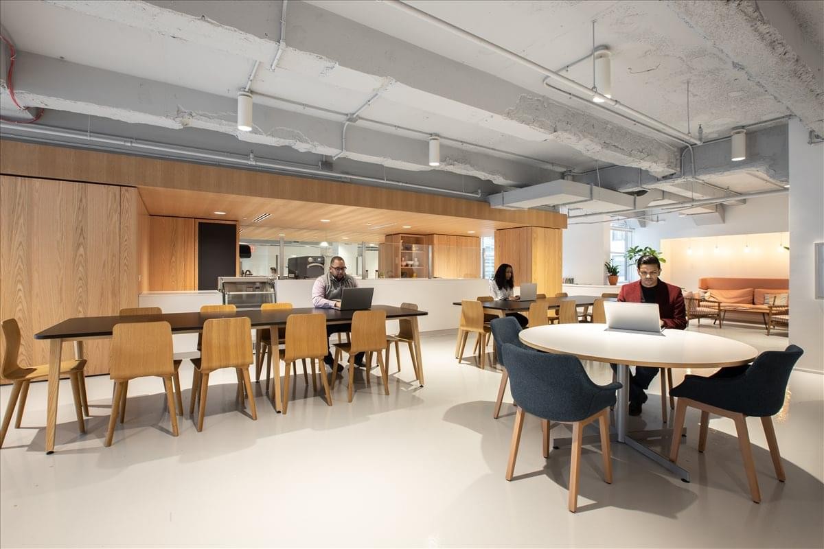 Light-filled communal lounge and café area with diverse seating options and wood-paneled walls.