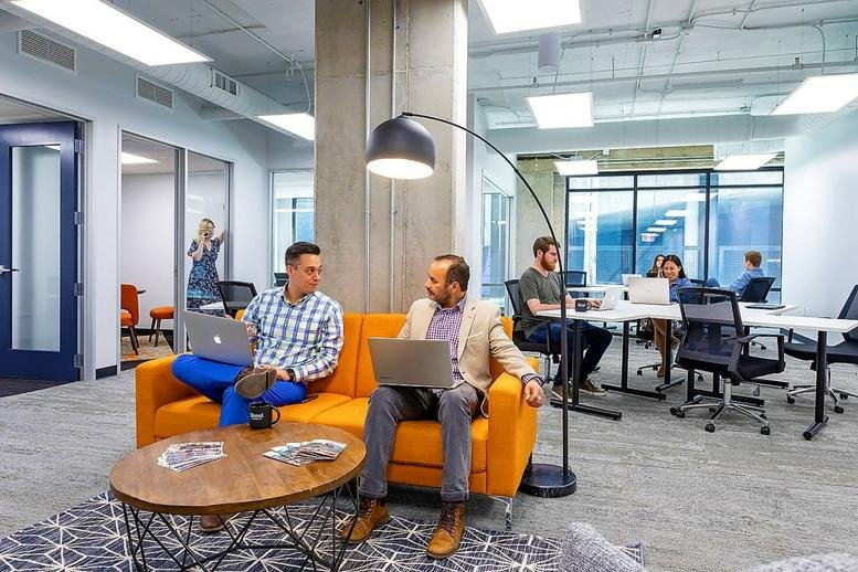Vibrant breakout area at 405 W Superior St featuring an orange sofa and curved floor lamp.