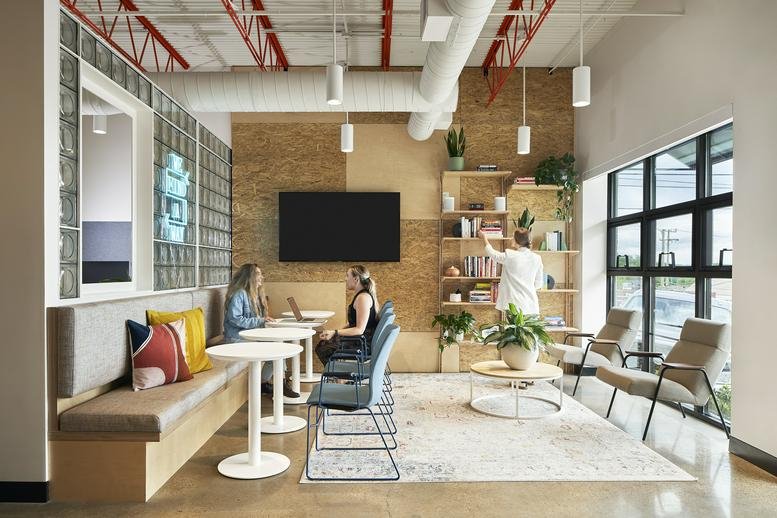 Spacious communal lounge and coworking area with a large wall-mounted screen and banquette seating.