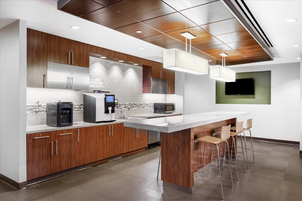 Modern breakroom kitchen with dark wood cabinetry, marble counters, and a breakfast bar.