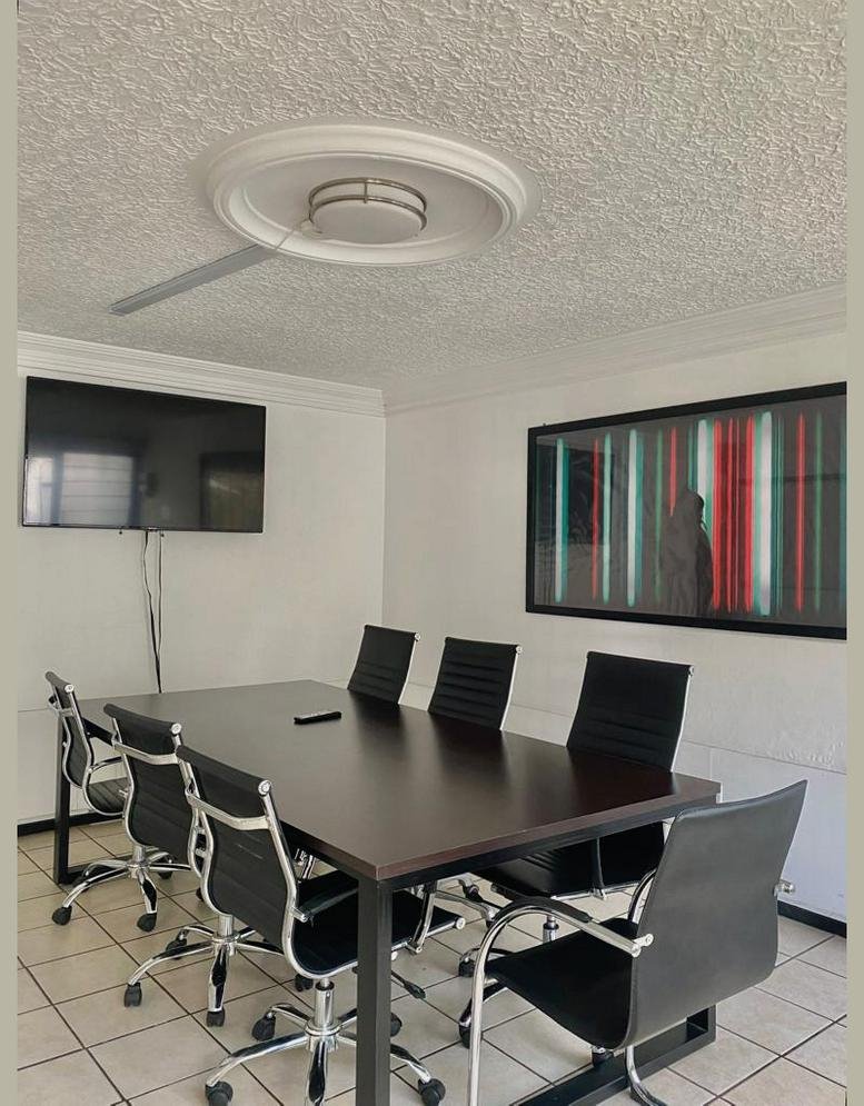 Modern meeting room featuring a dark wood table, black leather chairs, and a large wall-mounted screen.