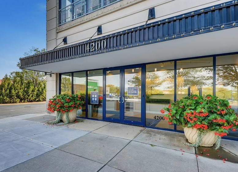 Exterior entrance of Office Evolution Easton at 4200 Regent Street with glass doors and potted flowers.