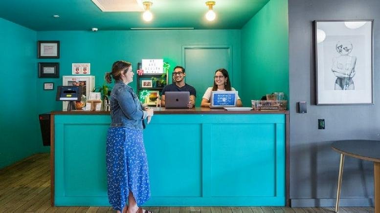 Bright reception area at 429 Lenox Avenue featuring a bold teal desk and wall with friendly staff.
