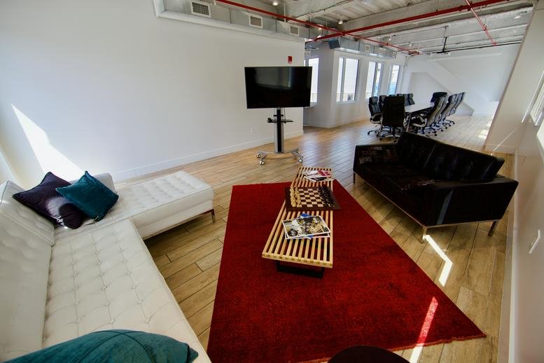 Modern lounge area with white sectional sofa and a red rug.