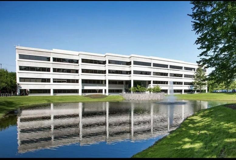 Exterior view of the white facade and lakeside reflection at Ridgebury Corporate Center.