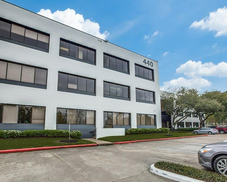 Wide exterior view of the white four-story office building at 440 Benmar Drive.