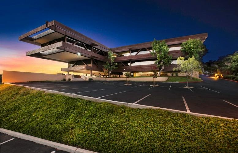 Exterior sunset view of the multi-level timber and glass building at The Timbers.