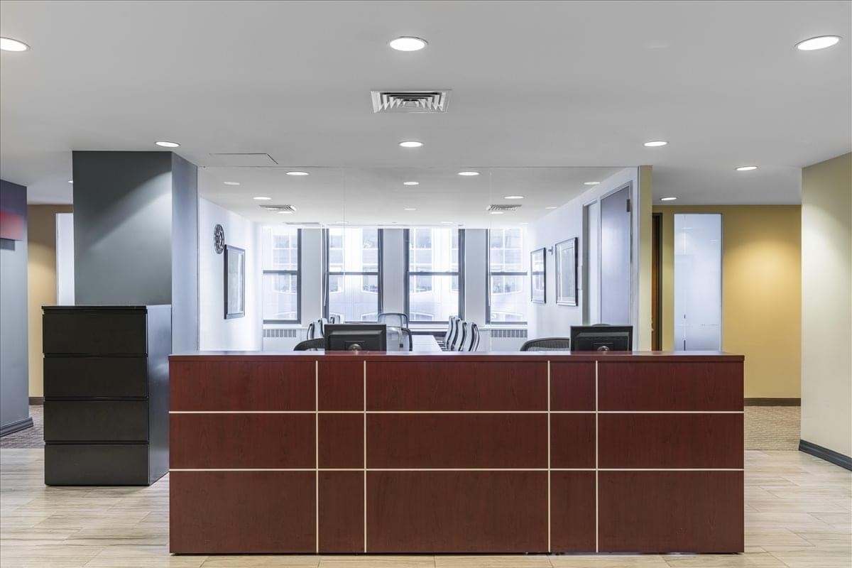 Professional reception area at 445 Park Avenue, Suite 900/1000, Midtown, New York with a wood-paneled desk.