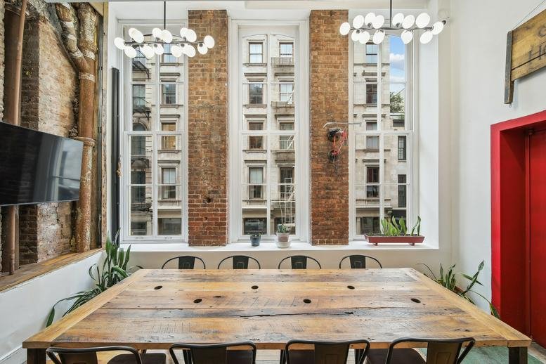 Sunlit communal space at 447 Broadway, 2nd Floor, Soho, New York with wooden tables and brick accents.