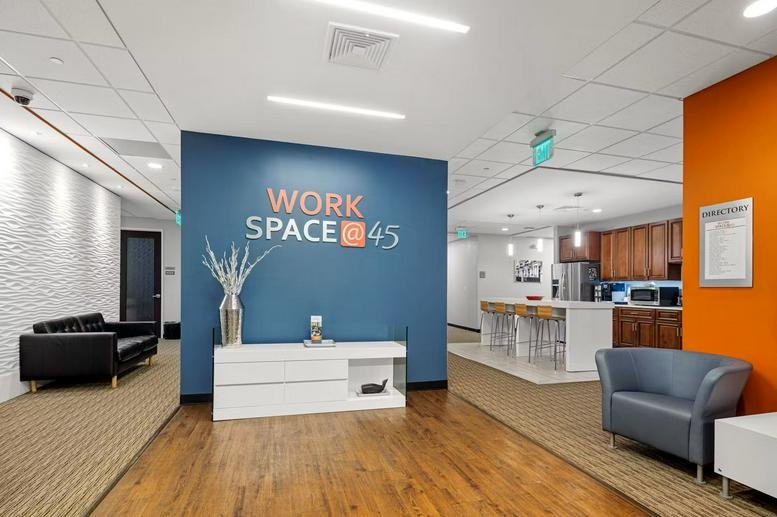 Reception lobby at Work Space @ 45 with a blue branded wall and white desk.