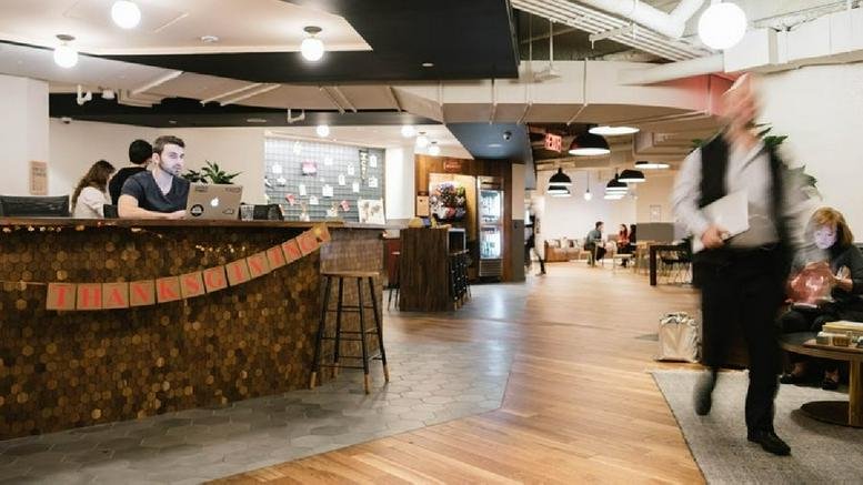 Spacious wood-floored reception area with a textured front desk and warm lighting.