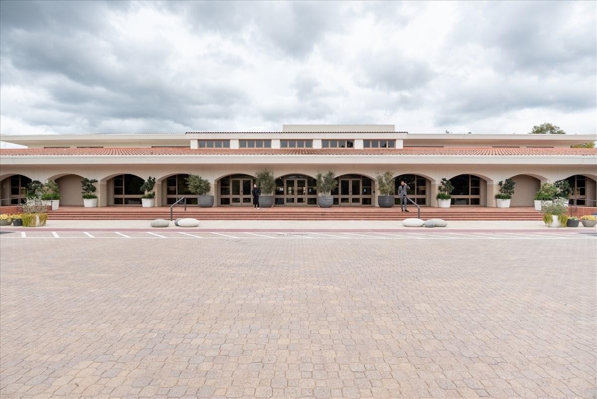 Exterior view of the arched facade and wide stone plaza at 4500 Park Granada Boulevard Suite 202.