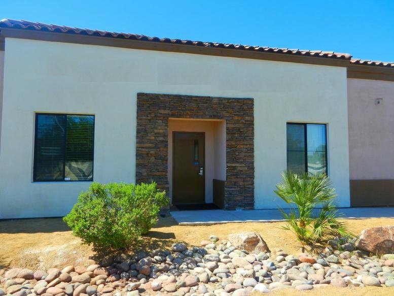 Exterior view of the tan building facade and stone-framed entrance at 4525 S. Sandhill Road.