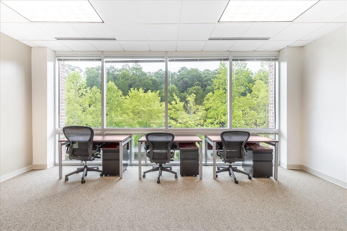 Spacious three-person office suite at 4555 Mansell Road with wide window views of lush greenery.