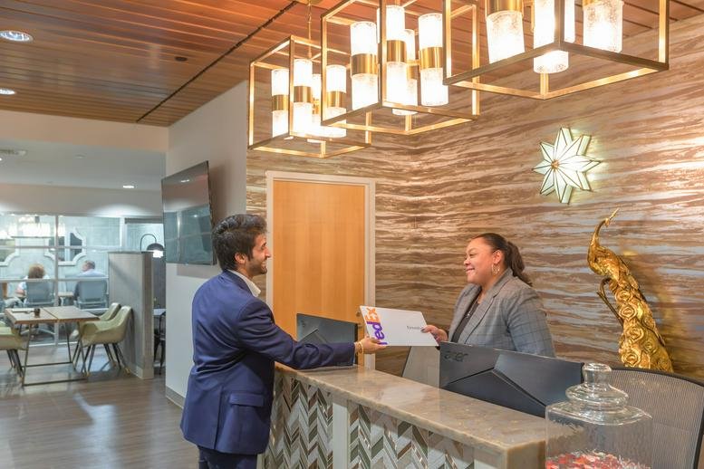 Reception desk at 48 Wall Street, Suite 1100 with wood feature walls and modern geometric lighting.