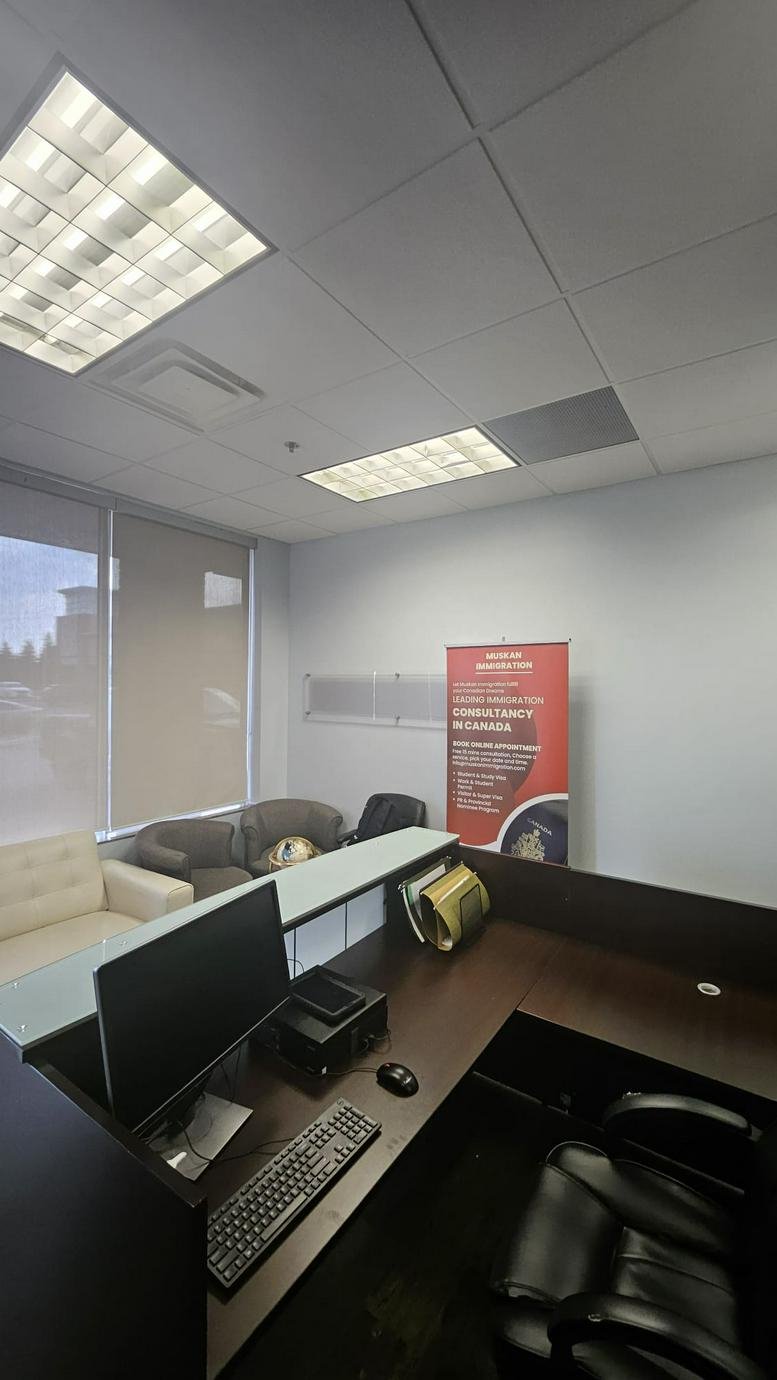 Modern reception area featuring a dark wood desk, glass partitions, and a red brand banner.