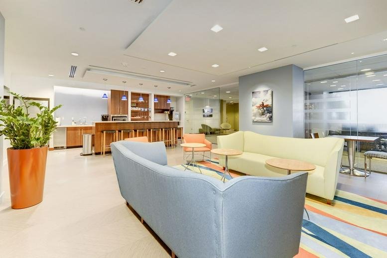 Spacious communal lounge at 4800 Hampden Lane, Suite 200 with modern sofas, plants, and a colorful rug.