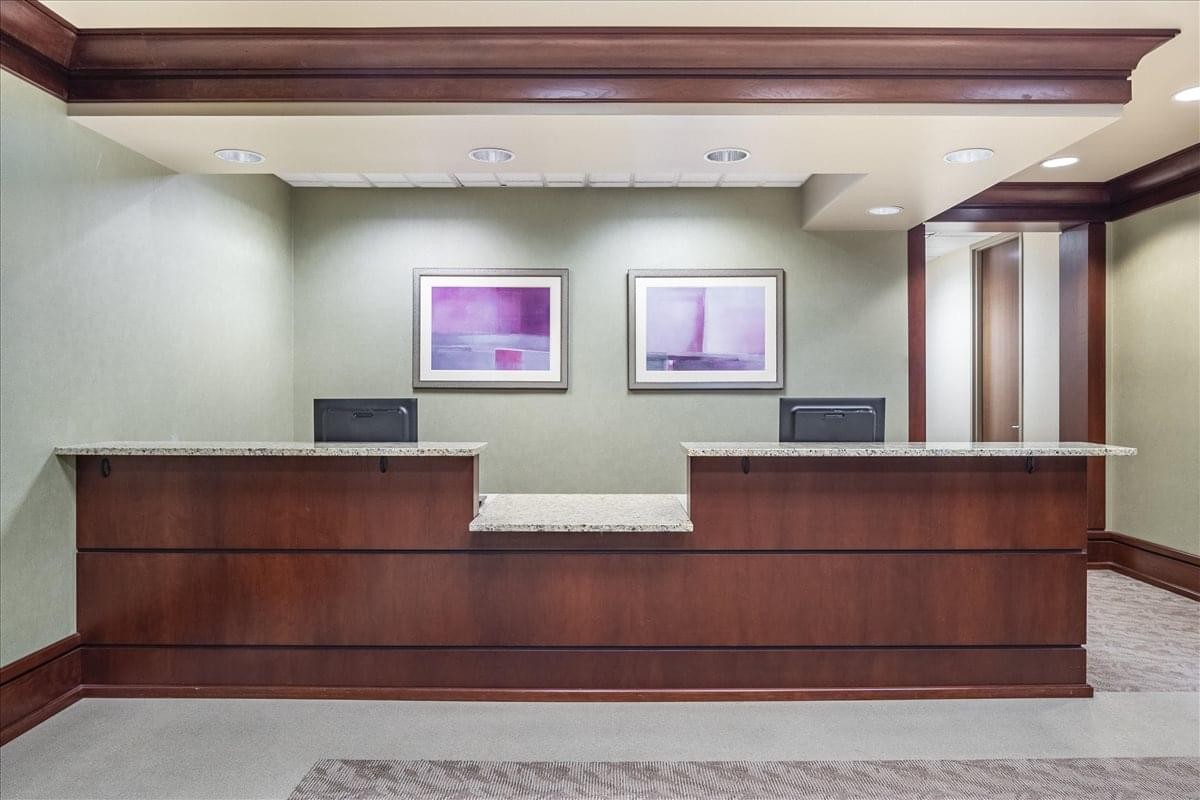 Professional reception area with a dark wood desk at 4870 Sadler Road, Suite 300.