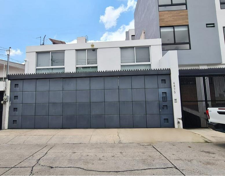 Exterior view of the Providencia Business Center, Zapopan featuring a modern white facade and large dark gate.