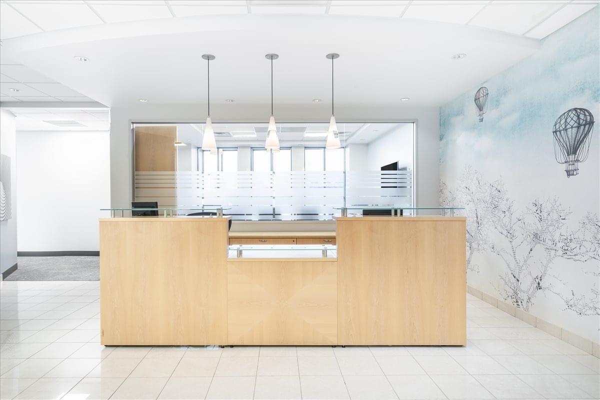 Bright reception area for 495 Grand Boulevard, Suite 206 with a light wood desk and artistic wall mural.